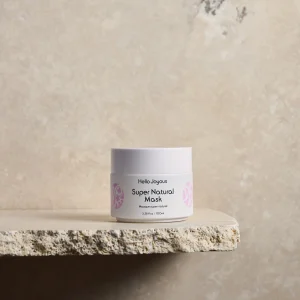 super natural mask in twist cap jar against plain backdrop a product image