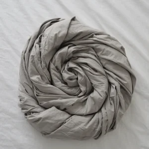 light grey flat sheet rolled into pinwheel against white sheet